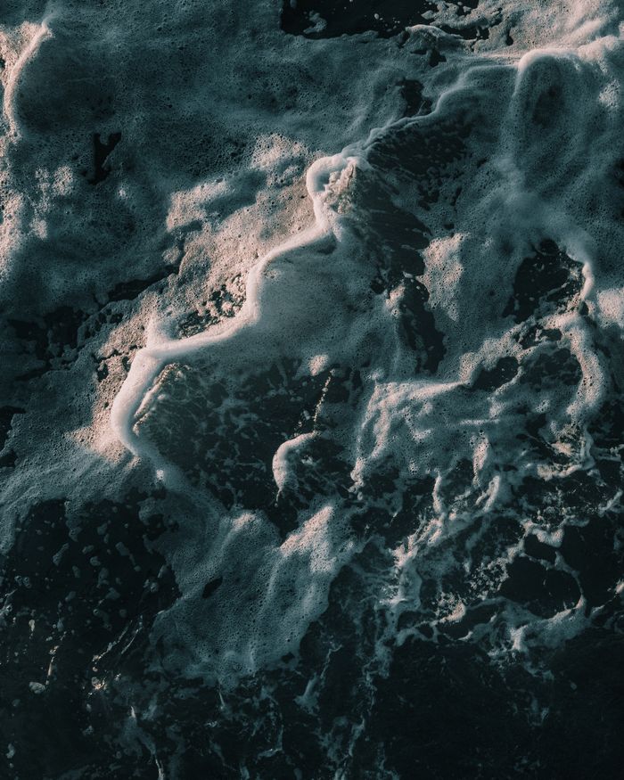 A dramatic aerial shot of ocean waves creating frothy patterns off the coast of Swakopmund, Namibia.